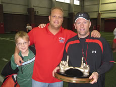 Preston Christensen and his son, Will, with Coach Kyle Whittingham holding the bronzed U.